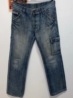 Diesel jeans/cargobyxor - Ett par perfekta Diesel byxor i tvättad denim med flera fickor på sidorna och bak. Byxorna har raka ben och bälteshällor. Knappt använda och så snygga, säljer för att de är för små för mig.