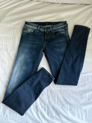 Replay skinny jeans blå - Säljer ett par snygga Replay jeans i tvättad blå färg med skinny passform. Klassisk femficksmodell med Replay-logga på fickan och coola kontrastsömmar på bakfickorna. Jeansen har normal midja och är gjorda i stretchigt denim för skön passform.