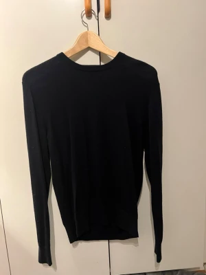 Marinblå stickad tröja med rund hals - En enkel och stilren marinblå stickad tröja med rund halsringning och långa ärmar. Tröjan har en rak passform och ribbade muddar vid ärmslut och nederkant. Perfekt basplagg för lager på lager och funkar till det mesta.