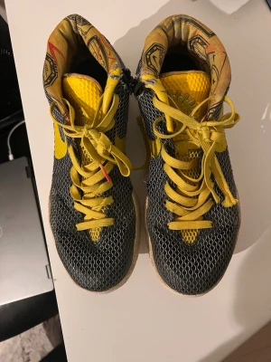 Nike Kyrie 1 LTD Limited Rise Black Yellow size 10 - The Nike Kyrie 1 LTD Limited Rise Black Yellow size 10 is a new deadstock sneaker featuring a mid-top silhouette with a vibrant yellow colorway. This limited edition model released in 2015 as part of the Nike Kyrie product line, designed for basketball performance and activewear occasions. Made with lightweight mesh upper material and a comfortable foam insole, these athletic shoes are perfect for men looking for a stylish and functional addition to their collection.