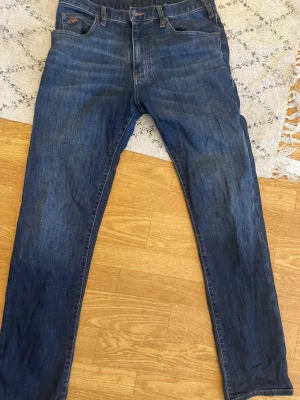 Mörkblå raka jeans från Evisu - Säljer ett par mörkblå jeans från EWA med klassisk femficksmodell och raka ben. Jeansen har en enkel design utan mönster och är tillverkade i bomull för en bekväm känsla. Perfekta till en avslappnad stil.