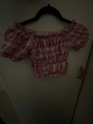 Barn T-shirt  - Supersöt rosa och vit topp med volangdetaljer. Toppen har korta puffärmar och ett mönster som ger en romantisk vibe. 