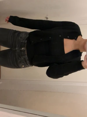 Svart stickad kofta  - Söt stickad svart kofta från H&M med knäppning framtill och långa ärmar. Koftan har en rak passform och är gjord i ett mjukt, skönt material som passar perfekt till alla tillfällen. Stilren och lättmatchad till olika outfits. Koftan är i storlek S, använd några fåtal gånger. 