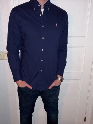 Mörkblå skjorta från Ralph Lauren - Mörkblä skjorta från Ralph Lauren i storlek M.  Fint skick till ett bra pris. Nypris: 1995kr. Mitt pris: 349kr. Vid frågor eller funderingar, tveka inte att höra av dig.