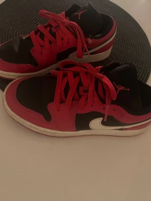 Svarta och röda Air Jordan sneakers - Säljer ett par Air Jordan sneakers med svart och röd ovandel, vita sulor och röda skosnören. Storlek 36