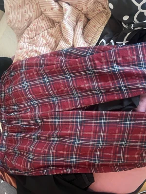 Pyjamas byxor - Säljer ett par snygga rutiga shorts från Lot i rött, blått och vitt. De har en klassisk rutig design och är perfekta för dig som vill ha en avslappnad men ändå stilren look. Shortsen är tillverkade i ett mjukt och bekvämt material.