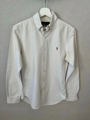 Ralph Lauren Skjorta - Stilren skjorta ifrån Ralph Lauren i färgen vit och modellen slim fit. Mycket bra skick och passar till allt, vid frågor eller funderingar är det bara att höra av sig! 😁