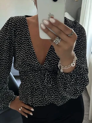 Svart prickig blus med v-ringning - Trendig svart och vit prickig blus från Zara som inte säljs längre. Väldigt smickrande! Lånad bild