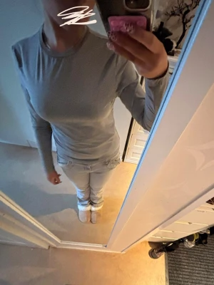 Grå långärmad topp  - En enkel och stilren grå långärmad topp med rund hals, som sitter bekvämt mot kroppen. Perfekt att matcha med jeans eller kjol för en clean look.