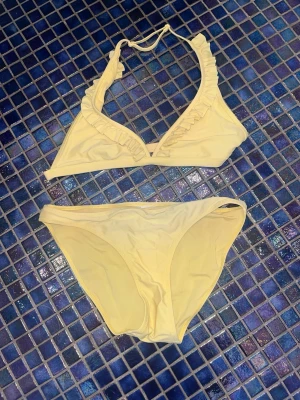 Ljusgul bikini med volangdetalj - Säljer den här super söta bikinin. Som är perfekt till sommaren. Vet tyvärr ej vart den är i från då det ej stod någon lapp i. Stod inte häller någon storlek, men skulle gissa på att den passar en XS/S. TAR GÄRNA EMOT PRISFÖRSLAG 