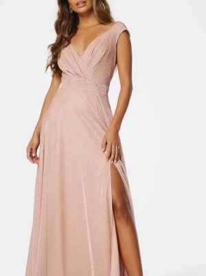 Balklänning  - Supersnygg långklänning i champagnefärg med glittrigt tyg och v-ringad. Klänningen har en slits framtill och är ärmlös. Den är endast använd en gång. Det står att den är storlek 10 uk