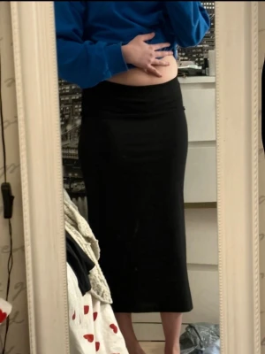 Svart långkjol med slits - En stilren svart långkjol med rak passform och slits baktill. Kjolen är enkel och passar perfekt till många olika outfits. Tillverkad i ett mjukt material som känns bekvämt mot huden.🥰