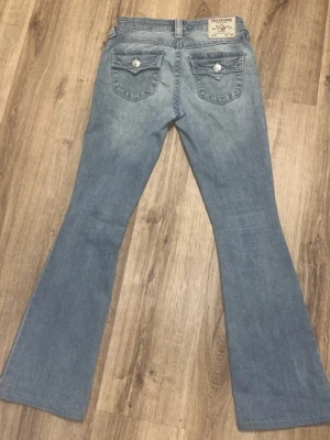 bootcut jeans True Religion - Säljer ett par ljusblå bootcut jeans från True Religion då det var för korta för mig vid fötterna. De är i storlek w24 och i stilen Becca, bootcut. De är i väldigt bra skick och har inget slitage alls. 💗💗