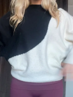 Svartvit stickad tröja med färgblock - Snygg stickad tröja i svart och vitt med cool färgblock-design. Tröjan har rund halsringning och långa ärmar. Perfekt för dig som gillar en trendig och avslappnad stil. Köpt i Paris