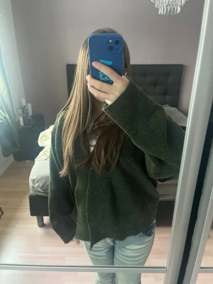 Mörkgrön oversized kofta - Mysig mörkgrön kofta med oversized passform och långa ärmar. Koftan är stickad i ett mjukt material och har en öppen front utan knappar. Det finns även ett snöre man kan knyta runt till.