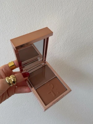 Patrick Ta bronzer duo She’s Sculpted  - Snygg bronzer duo från Patrick Ta i ett lyxigt guldrosa etui med spegel. Innehåller två nyanser: en matt och en krämig bronzer i bruna toner. Färg: She’s Sculpted.  Perfekt för att skapa en solkysst look och contour. Praktisk för necessären och enkel att applicera. Testad en gång 
