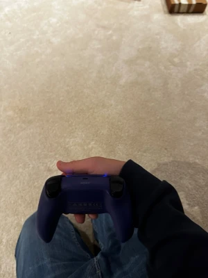 Sony DualSense trådlös handkontroll lila - Säljer en snygg lila Sony DualSense handkontroll till PlayStation 5. Kontrollen har en modern design med svarta detaljer, två analoga spakar, touchpad och inbyggd mikrofon. Perfekt för gaming och passar bra i handen. Materialet är plast med matt finish.