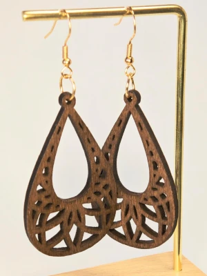 Ultralätta Bruna träörhängen i organisk design  - Eleganta örhängen med en kombination av trä och bladmotiv.  Perfekt för att komplettera din stil med en naturlig och bohemisk touch.  Trädelen är ca 5 cm lång. Motivet är fäst på högkvalitativa örhänges-krokar i rostfritt stål.  Nya med etikett.