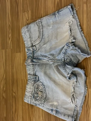 Ljusblå denimshorts med broderade fickor - Ljusblå denimshorts . Fickorna bak har snygga broderade detaljer som ger extra stil. Klassisk femficksdesign och knappstängning framtill. Perfekta för dig som vill ha en cool och avslappnad look.