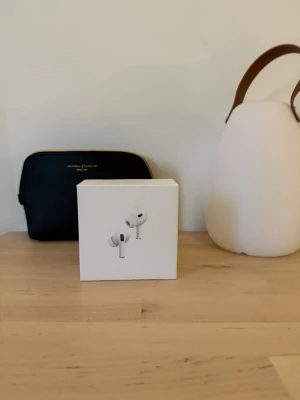 Apple AirPods Pro trådlösa hörlurar - Säljer ett par vita Apple AirPods Pro med tillhörande laddningsetui och originalförpackning. Hörlurarna är in-ear och har en stilren, kompakt design i plast. Perfekt för dig som vill ha grymt ljud och smidig anslutning till din iPhone eller andra Apple-enheter.