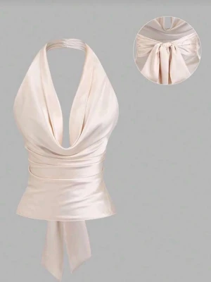 Champagnefärgad halterneck topp - Snygg champagnefärgad halterneck topp i satin med knyt i ryggen. Toppen har djup urringning och öppen rygg, perfekt för att sticka ut. Materialet är glansigt och mjukt vilket ger en lyxig känsla. Säljer då jag råkade beställa 2 st