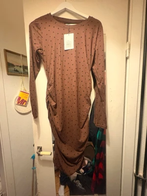 Brun långklänning med svarta hjärtan - En splitter ny helt oanvänd brun lång klänning med svarta hjärtan. Har aldrig använt inte ens provat då den kommer från en mystery bag från MollyandMy. Är i stl L/M. Hämtas på Södermalm i Stockholm eller skickas till dig. Du bestämmer. Maila mig vid frågor. Med vänlig hälsning, Fanny.   
