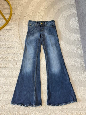 Blå utsvängda jeans Cheap Monday - Säljer ett par blå jeans från Cheap Monday med riktigt breda utsvängda ben och slitna detaljer. Jeansen har klassisk femficksmodell, dragkedja och knapp framtill samt en cool Cheap Monday-patch bak. Perfekta för dig som gillar retrostil! Säljs då de inte kommer till användning. Storlek 25/30. Använda 2 gånger.