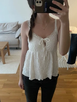 Vitt spetsigt linne från Gina - Supersöt vit linnetopp med spetsiga axelband och knyt framtill. Linnet är lite längre baktill, är från Gina Tricot i storlek S. Pris kan diskuteras, skriv privat vid intresse! 