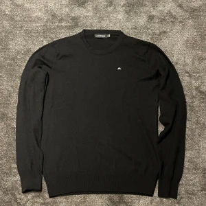 Svart Tröja från J Lindberg - En svart snygg tröja från J Lindberg med vitt broderat märke för en extra snygg touch. Skick som nytt, (passar 165-170)  hör av dig vid frågor eller funderingar 😉