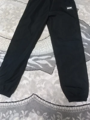 Svarta mjukisbyxor från SNOW - Svarta mjukisbyxor från SNOW med resår i midjan och vid bensluten. Byxorna har en enkel och clean design, perfekta för chill dagar. Tillverkade i mjukt material som känns skönt mot huden. Står se på storleken fast jag har testat och den passar xs. PRIS KAN DISKUTERAS!