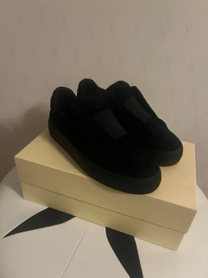 Axel Arigato helsvarta mocka strl 40 (Slutsålda - Säljer ett par Axel Arigato i helsvart mocka, storlek 40.  Modellen är designad utan skosnören. Slutsåld och finns inte längre att köpa. Bra skick och väl omhändertagna.  Stilrena och minimalistiska – passar till allt