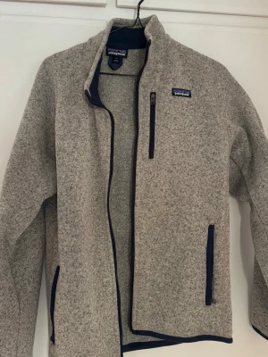Patagonia fleece - Oanvänd grå patagonia fleece, toppskick! inte använts sedan köp från naturkompaniet, färgen + modellen finns ej kvar att köpa på sidor längre. Storlek M, vid funderingar eller fler bilder är det bara att höra av sig. Då det är en så pass fin tröja så kommer jag inte gå ner i pris, då något lägre bud  inte känns värt att ta för en sån fleece. 