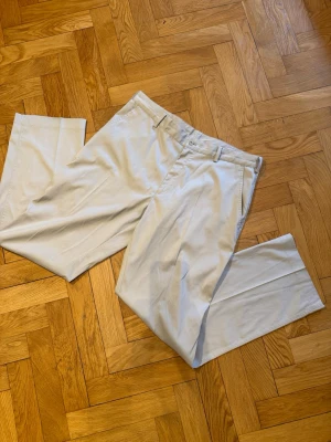 Nike golf byxor, 34/32 - Riktigt sköna Nike golfbyxor med storleken 34/32. De är i beige färg och riktigt skönt material. Byxorna är som nya men saknar prislapp Midjan är 46cm Längden från topp till tå är 107cm Bredden på byxbenen är 22,5cm Byxan är i storlek M men passar även storlek L.