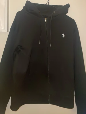 Svart kofta från Polo Ralph Lauren - Svart Ralph lauren zip hoodie som är i nytt skick 