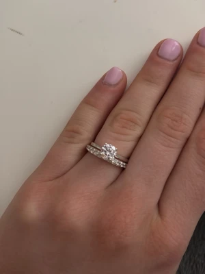 Silver ring-set med stenar - Säljer ett stilrent ring-set i äkta silver. Ena ringen har en stor, rund klar sten i mitten och den andra är dekorerad med små gnistrande stenar runt hela bandet. Perfekt för dig som gillar klassisk och elegant design. Dem kan bäras tillsammans eller separat. Använd ett fåtal gånger, från guldfynd i storlek 16