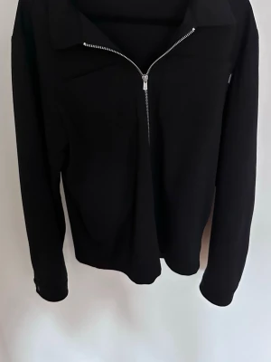 Overshirt - Snygg svart overshirt från Jack and Jones med halv dragkedja framtill och hög krage. Tillverkad i mjukt material som känns skönt mot huden. Perfekt för en avslappnad och stilren look. Långa ärmar och minimalistisk design utan tryck eller logga. Pris kan diskuteras vid snabb affär. 