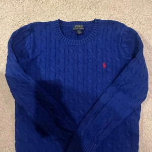 Blå stickad tröja från Ralph Lauren - Säljer en snygg blå stickad tröja från Ralph Lauren med det klassiska röda logotypen på bröstet. Den är i mycket bra skick och passar för vintern och sommaren! L i barnstorlek.