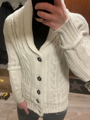Vit stickad cardigan - Otroligt snygg vit flätstickad cardigan. Passar perfekt till kallare väder. Modellen är 180cm, 75kg. Priset kan såklart diskuteras