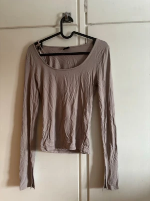 Beige långärmad topp Gina Tricot - En enkel och stilren beige långärmad topp från Gina Tricot. Slits i ärmarna, knappt använd❣️Strykes innan packning! Tunn material som sitter kroppsnära, perfekt till jeans