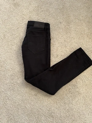 Tiger Of Sweden - Snygga svarta slim fit jeans med klassisk femficksdesign och knappgylf. Jeansen har en stilren look och passar perfekt till en avslappnad streetstyle. Materialet känns mjukt och stretchigt för extra komfort.