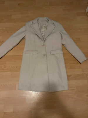 Beige kappa i ullmix - Märke: Ellos Storlek: 34, men passar mig som har 36/S Färg: Beige Material: Ullmix Nypris 799 kr. Mått (byst/midja/stuss): 80/64/88