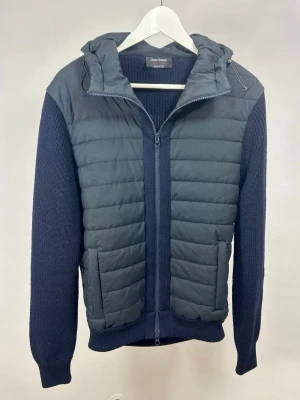 Gran Sasso Cardigan Navy - Sällsynt cardigan från Gran Sasso i nyskick. Ordinarie nypris ca 5000 kr. Modellen är 175 cm och väger 70 kg. Storlek 48 men passar S-M. Stickningen är i 100% ull och vadderingen i polyester. 