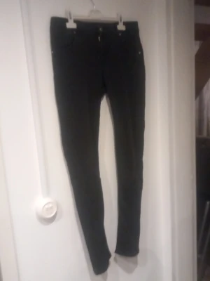 Svarta skinny jeans - Säljer ett par svarta jeans. Jeansen har klassisk femficksdesign, smal passform och stängs med knapp och dragkedja. Materialet är stretchigt för extra komfort och passform. Perfekta för dig som gillar en slimmad look.