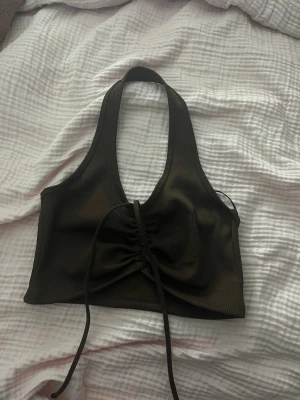 Brun  ribbad halterneck linnetopp - Snygg brun ribbad linnetopp med halterneck och snörning framtill. Toppen är croppad och har en tight passform som framhäver figuren. Perfekt att styla med höga jeans eller kjol för en trendig look.