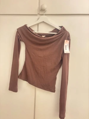 Brun topp från nelly - Säljer en super snygg topp från Nelly då den är för liten för mig☺️Skriv för fler bilder då toppen ser lite konstig ut hängandes för att tanken är att den ska sitta lite snett vid axeln🥰
