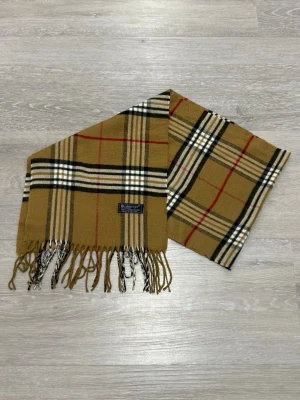 Beige Burberry Scarf – 100% Lambswool – Made in England - Beautiful and timeless Burberry scarf in the classic beige/camel check pattern with black, white, and red lines. Adds elegance to any outfit!  ✔️ 100% lambswool🧵 ✔️ Made in England😁 ✔️ Authentic Burberry✅ ✔️ Slightly used, in very good condition👍 ✔️ No visible stains or marks🧣  Soft, warm, and perfect for autumn and winter.  I can ship quickly or meet face-to-face depending on location😄🙌