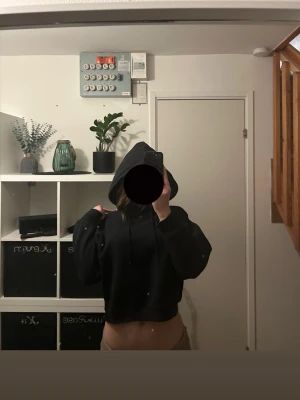 Svart cropped hoodie med huva - Säljer en svart cropped hoodie med huva och långa ärmar. Hoodien har en avslappnad passform och dragsko i huvan. Perfekt för en chill och trendig look. Materialet känns mjukt och bekvämt mot huden.