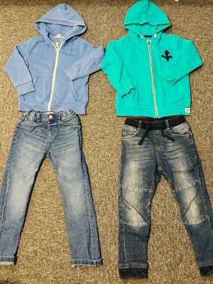 Blå och turkos hoodies med dragkedja - Två hoodies i olika färger, en ljusblå och en turkos, båda med dragkedja framtill och huva. Den turkosa har en svart detalj på. passar till jeans eller mjukisbyxor. Sköna och enkla att matcha med det mesta. 