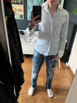 Ljusblå skjorta med knappar - Snygg ljusblå bomullsskjorta från Italien . Skjortan har lång ärm och en slim passform som sitter tajt mot kroppen. Skriv vid fundering!