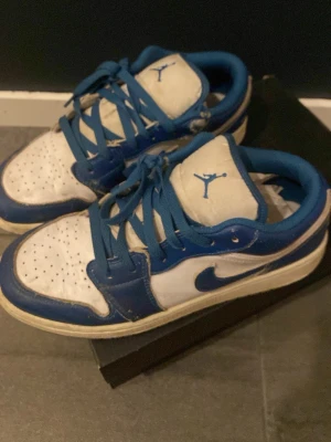 Air Jordan 1 Low SE blå/vit - Säljer ett par Air Jordan 1 Low SE sneakers i blått och vitt läder. Klassisk siluett med blå swoosh, blå snörning och Jumpman-logga på plösen. Perfekta för dig som gillar streetwear och vill ha en ikonisk sneaker i garderoben.